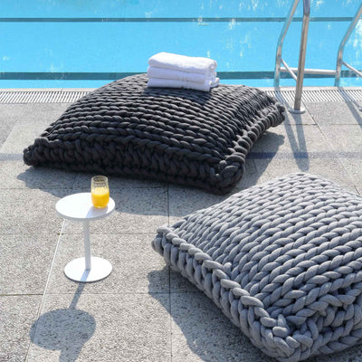 COVO Roxy Maxi Cushion by Rosanna Contadini. Chunky knit poufs in black and gray sit poolside with towels and juice.