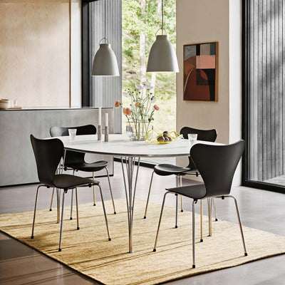 Fritz Hansen Superellipse™ B611 Table by Piet Hein. A modern dining space features black chairs around a white oval table.
