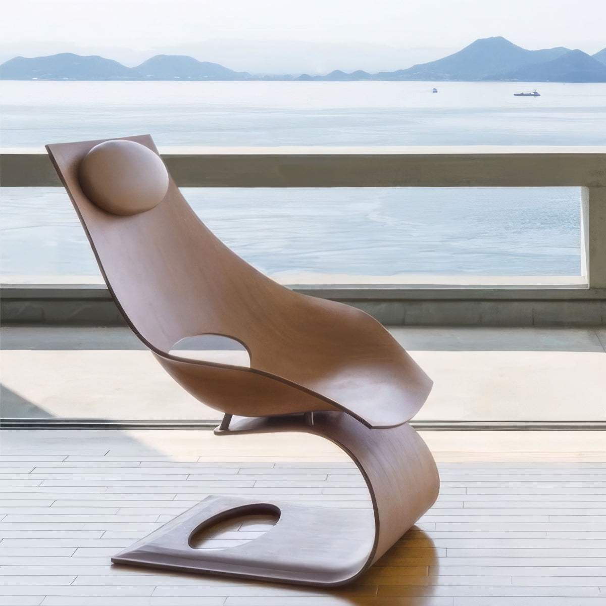 Carl Hansen & Søn TA001P Dream Chair by Tadao Ando. A sculptural wooden chair with curved forms sits on a waterfront deck.