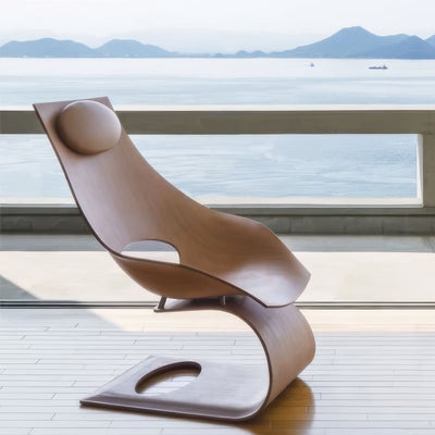 Carl Hansen & Søn TA001P Dream Chair by Tadao Ando. A sculptural wooden chair with curved forms sits on a waterfront deck.