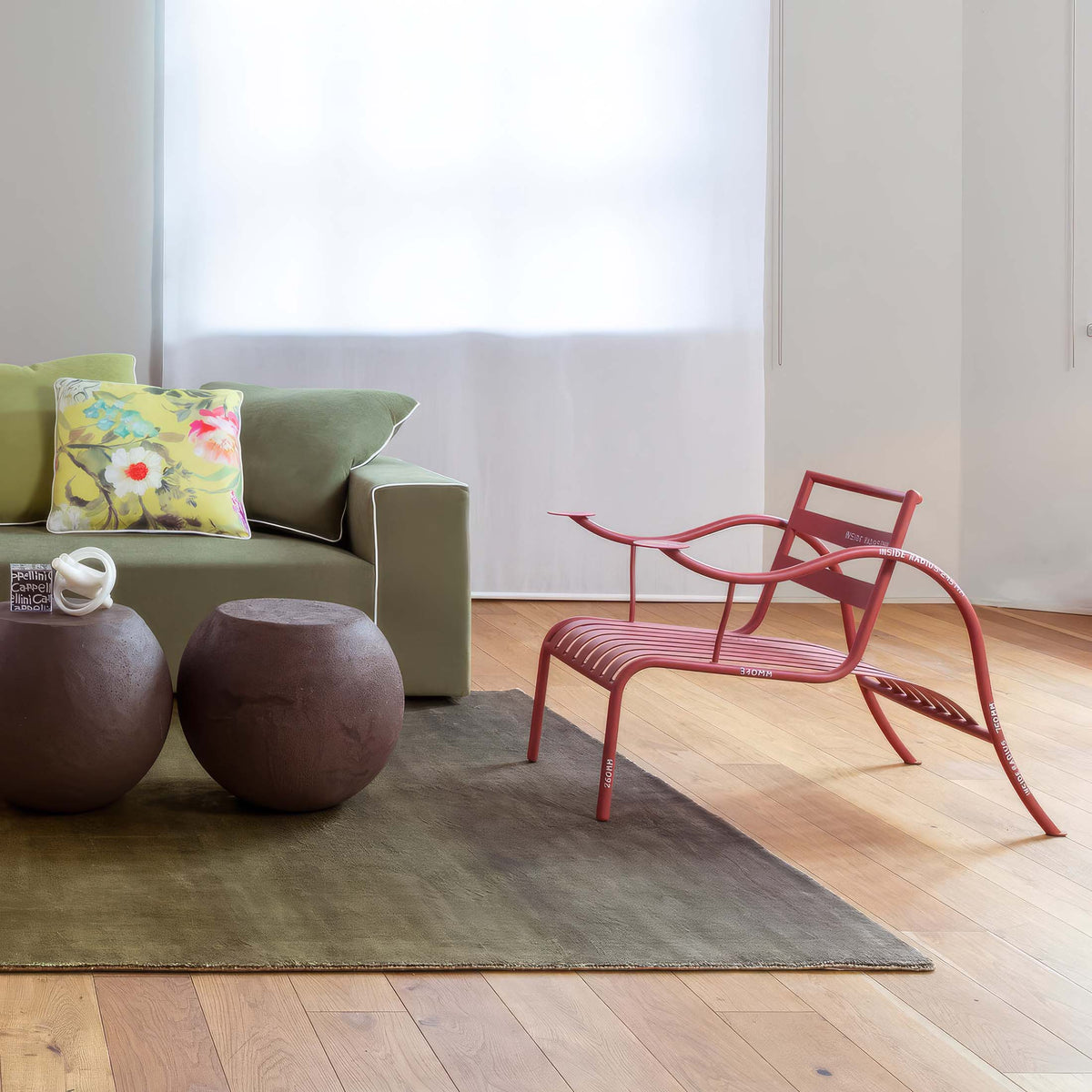 Cappellini Thinking Man's Chair by Jasper Morrison. A red curved chair sits on light wood flooring beside a gray rug.