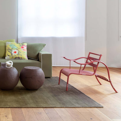 Cappellini Thinking Man's Chair by Jasper Morrison. A red curved chair sits on light wood flooring beside a gray rug.