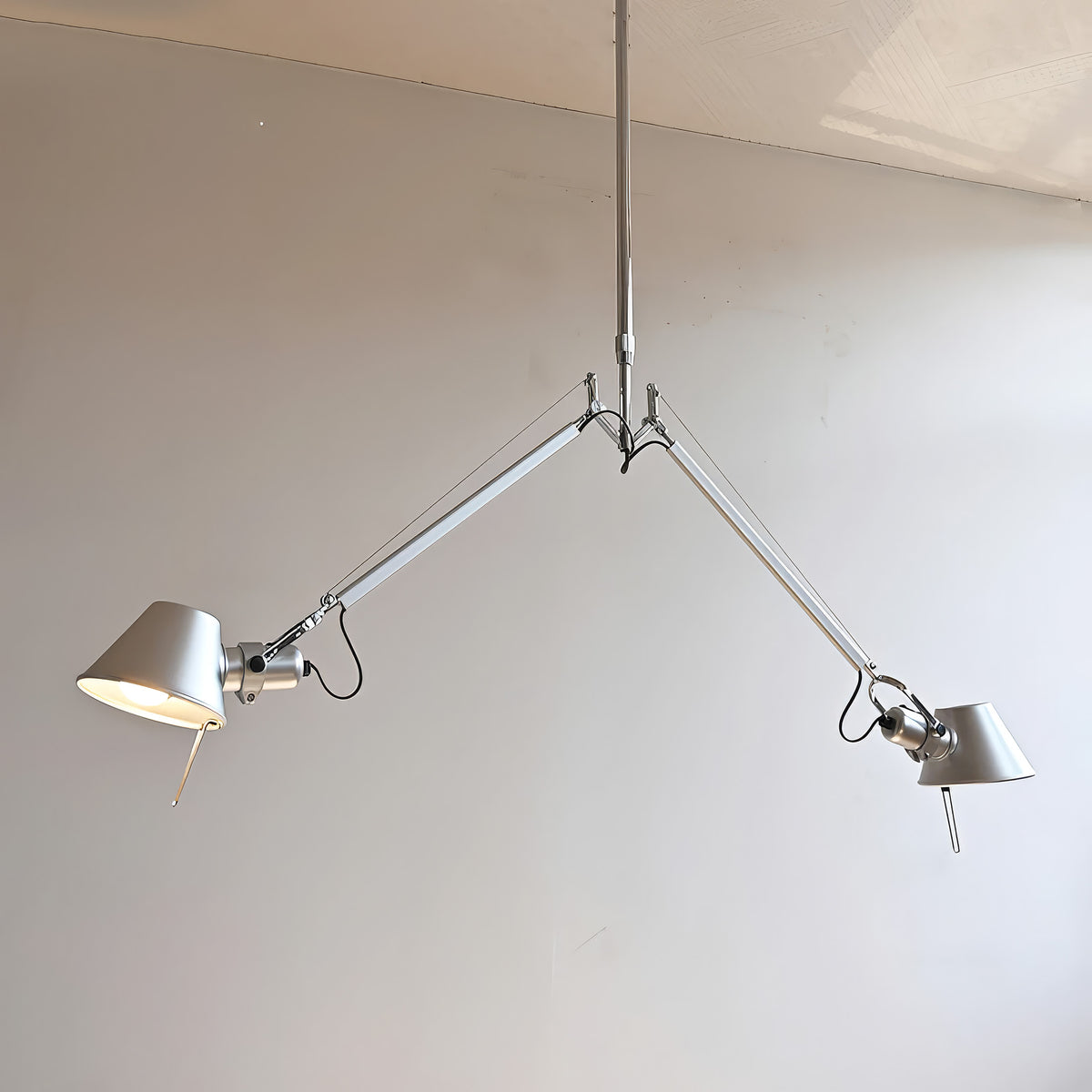 Artemide Tolomeo Due Bracci Suspension by Michele De Lucchi. Two silver metal lamps hang from a brushed steel frame.
