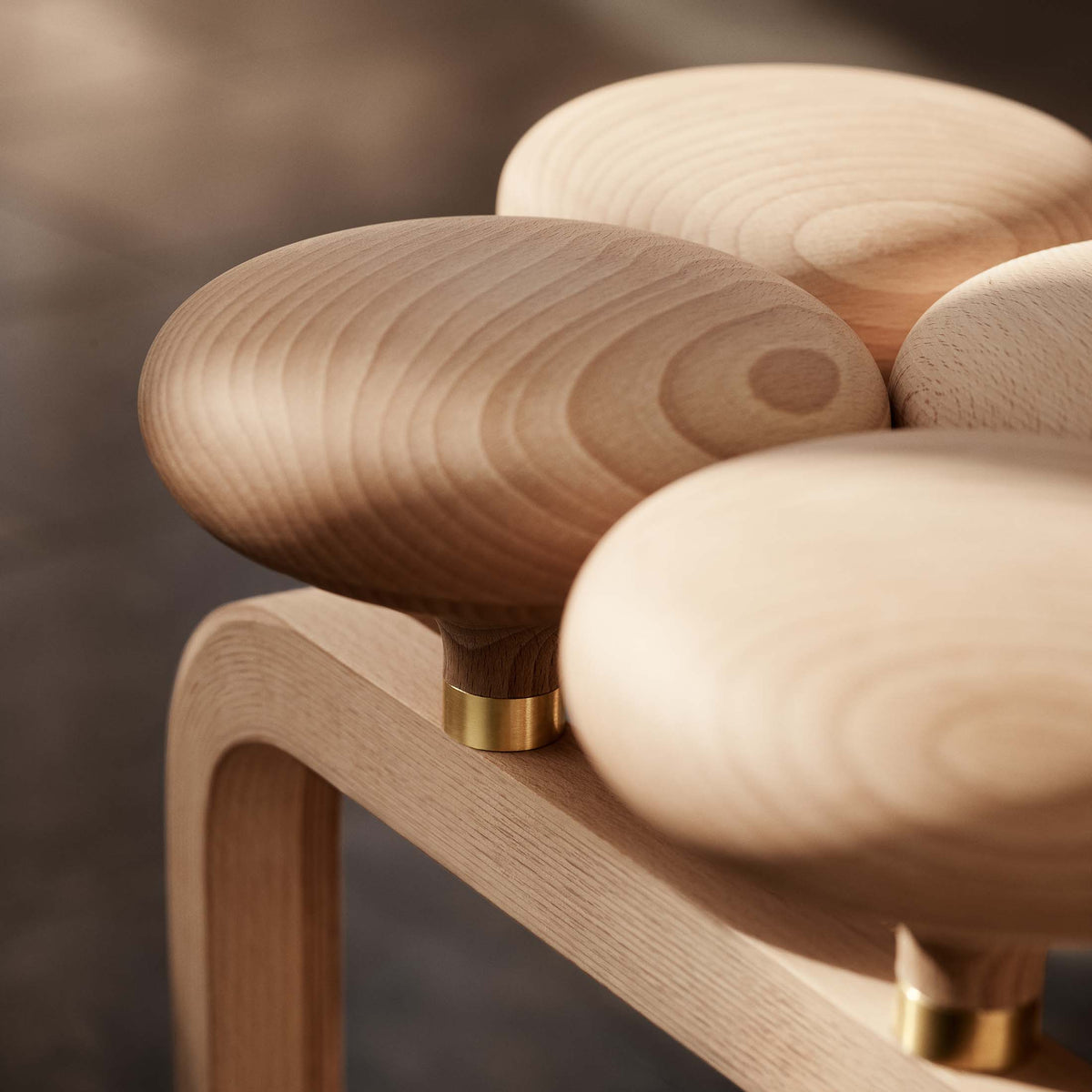 Fritz Hansen JU01™ Utzon Stool by Jørn Utzon. Wooden spheres with brass accents rest on a natural oak frame.