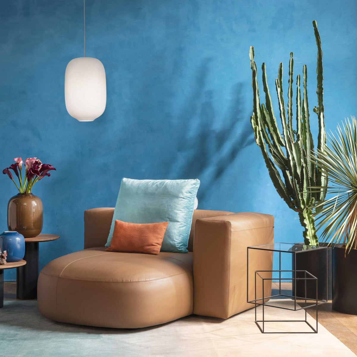 Cappellini Litos by Sebastian Herkner. A tan leather chair sits against a vibrant blue wall with modern decor.