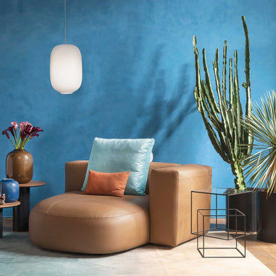 Cappellini Litos by Sebastian Herkner. A tan leather chair sits against a vibrant blue wall with modern decor.