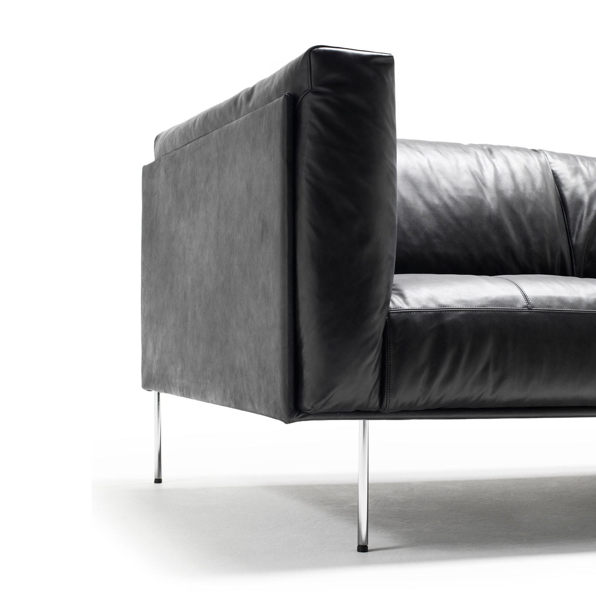 Living Divani Rod Sofa by Piero Lissoni. A modern sofa features black leather and gray fabric with sleek metal legs.